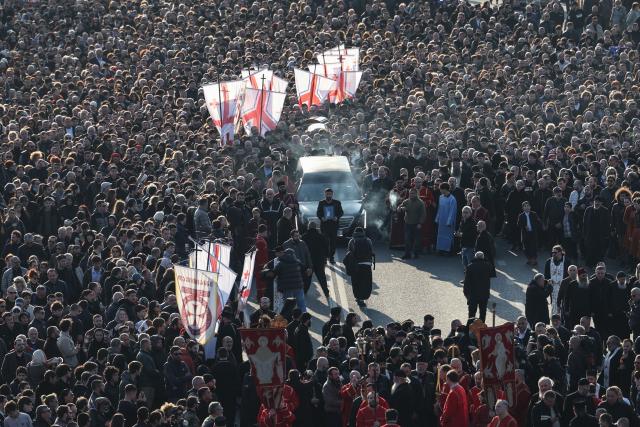 Mourners follow the hearse transporting the coffin with the body of the late Georgia's Orthodox Patriarch Ilia II prior to a memorial service to be held at the Sameba Cathedral in Tbilisi on March 18, 2026. Georgian Orthodox Church leader Ilia II died on March 17, 2026 aged 93, the church said, after nearly half a century at the helm of one of the country's most powerful institutions. (Photo by Giorgi ARJEVANIDZE / AFP)