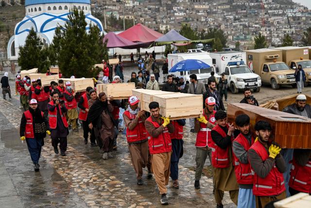 Afghan Red Crescent Society volunteers carry the coffins after offering funeral prayers for victims of a Pakistani air strike on a drug rehabilitation centre, during a mass burial ceremony at the Badam Bagh Hilltop in Kabul on March 18, 2026. The Taliban authorities have said that around 400 people were killed and more than 200 wounded on March 16 night, in the deadliest attack yet in the recent upsurge in violence between the two neighbours. (Photo by Wakil KOHSAR / AFP)