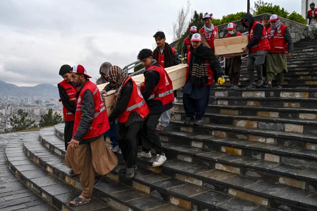 Afghan Red Crescent Society volunteers carry the coffins after offering funeral prayers for victims of a Pakistani air strike on a drug rehabilitation centre, during a mass burial ceremony at the Badam Bagh Hilltop in Kabul on March 18, 2026. The Taliban authorities have said that around 400 people were killed and more than 200 wounded on March 16 night, in the deadliest attack yet in the recent upsurge in violence between the two neighbours. (Photo by Wakil KOHSAR / AFP)