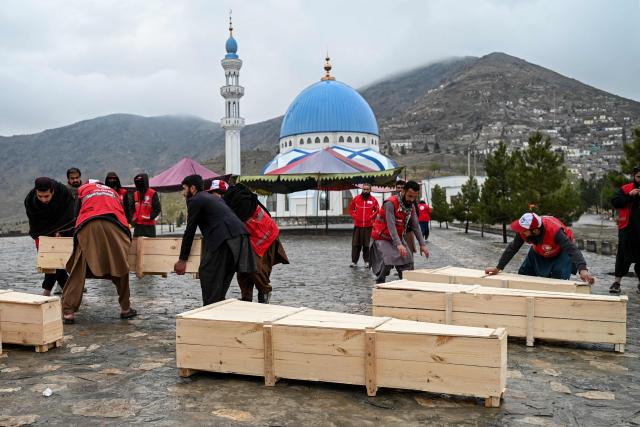 Afghan Red Crescent Society volunteers carry the coffins after offering funeral prayers for victims of a Pakistani air strike on a drug rehabilitation centre, during a mass burial ceremony at the Badam Bagh Hilltop in Kabul on March 18, 2026. The Taliban authorities have said that around 400 people were killed and more than 200 wounded on March 16 night, in the deadliest attack yet in the recent upsurge in violence between the two neighbours. (Photo by Wakil KOHSAR / AFP)