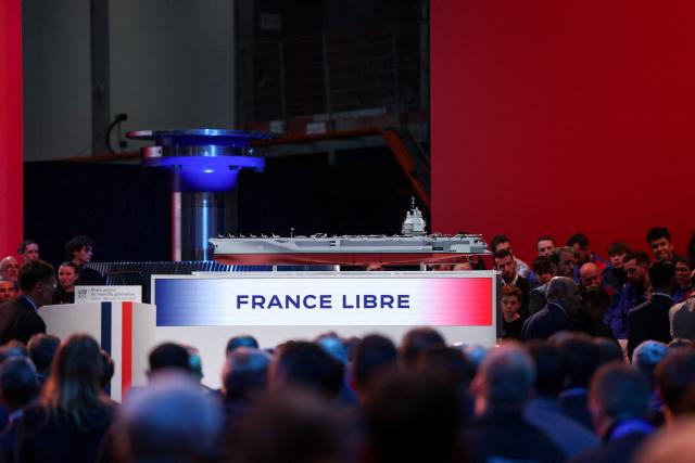 This photograph shows the model of a ship named "France Libre" as French President visits the construction site of Naval Group Nantes-Indret, where the next generation French aircraft carrier is under construction, in Indret, western France, on March 18, 2026. The French president unveiled the name of France's next aircraft carrier: "France libre", as the country looks to reinforce its status as a major maritime power. Once completed, the new nuclear-powered flagship, which is set to replace the country's sole aircraft carrier, the Charles de Gaulle, will be the largest warship ever built in Europe. (Photo by Gonzalo Fuentes / POOL / AFP)