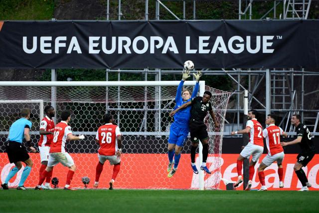 Ferencvaros' Hungarian goalkeeper #01 Adam Varga jumps for the ball with Ferencvaros' French midfielder #75 Lenny Joseph during the UEFA Europa League last 16 second leg football match between SC Braga and Ferencvaros at Municipal stadium of Braga on March 18, 2026. (Photo by Miguel RIOPA / AFP)