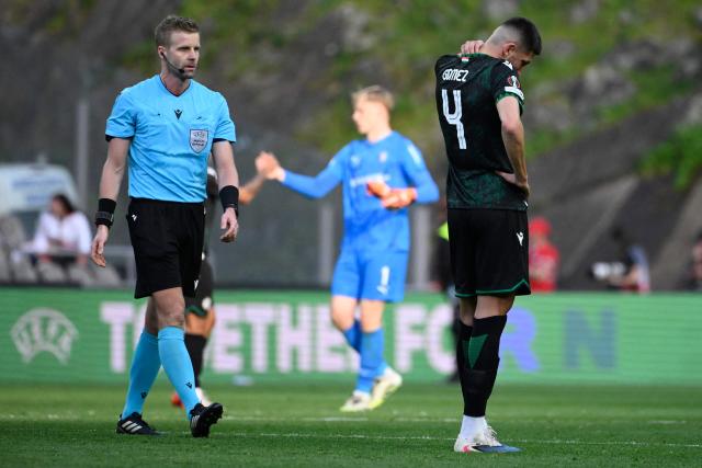 French referee Francois Letexier walks past Ferencvaros' Argentinian defender #04 Mariano Gomez at the end of the UEFA Europa League last 16 second leg football match between SC Braga and Ferencvaros at Municipal stadium of Braga on March 18, 2026. (Photo by Miguel RIOPA / AFP)