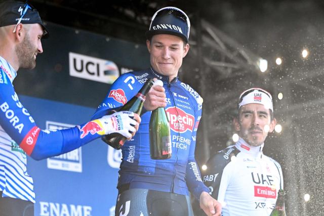 (LtoR) Red Bull-BORA-hansgrohe's cyclist Jordi Meeus (runner-up), Alpecin-Premier Tech's cyclist Jasper Philipsen (winner) and UAE Team Emirates-XRG's cyclist Juan Sebastian Molano (third placed) celebrate with champagne after the Nokere Koerse one-day cycling race in Kruisem on March 18, 2026. (Photo by ELIAS ROM / Belga / AFP) / Belgium OUT