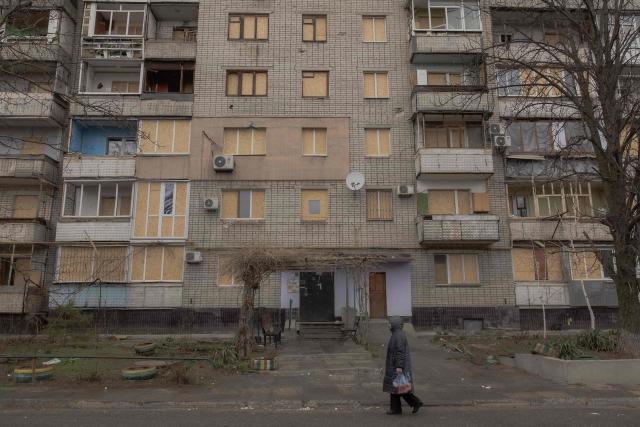 A woman walks past a residential apartment building that was recently damaged from a Russian air attack in Zaporizhzhia on March 18, 2026, amid the Russian invasion of Ukraine. (Photo by Roman PILIPEY / AFP)