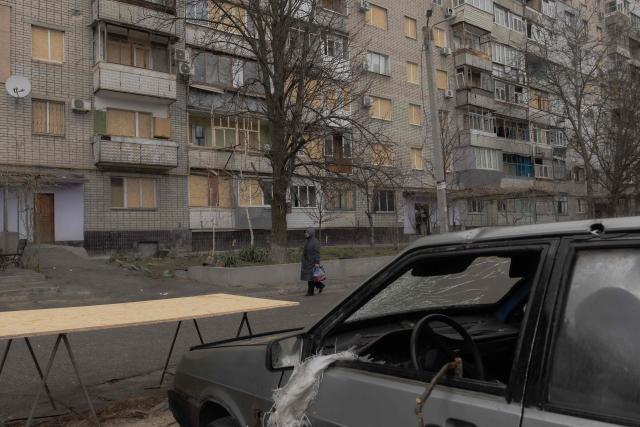 A woman walks past a residential apartment building that was recently damaged from a Russian air attack in Zaporizhzhia on March 18, 2026, amid the Russian invasion of Ukraine. (Photo by Roman PILIPEY / AFP)