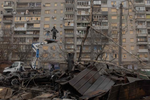 A Ukrainian municipal worker is lifted on a cherry picker at the site of a recent Russian air attack in Zaporizhzhia on March 18, 2026, amid the Russian invasion of Ukraine. (Photo by Roman PILIPEY / AFP)