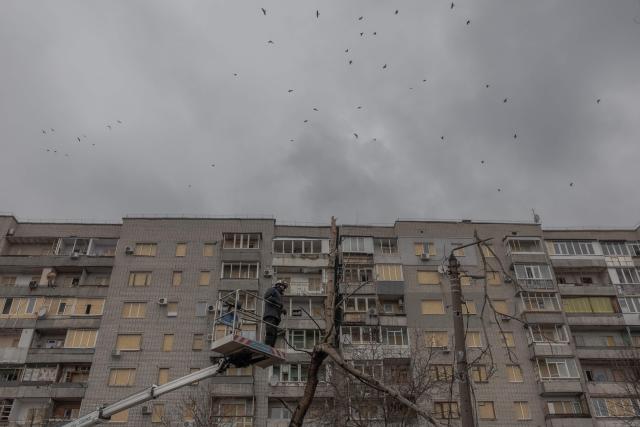 A Ukrainian municipal worker inspects the site of a recent Russian air attack in front of a damaged residential building in Zaporizhzhia on March 18, 2026, amid the Russian invasion of Ukraine. (Photo by Roman PILIPEY / AFP)