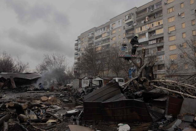 A Ukrainian municipal worker cuts down a tree at the site of a recent Russian air attack in front of a damaged residential building in Zaporizhzhia on March 18, 2026, amid the Russian invasion of Ukraine. (Photo by Roman PILIPEY / AFP)
