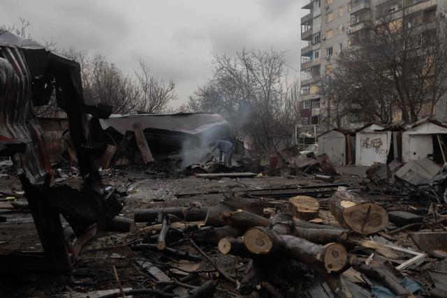 TOPSHOT - A man looks through debris at the site of a recent Russian air attack in front of a damaged residential apartment building in Zaporizhzhia on March 18, 2026, amid the Russian invasion of Ukraine. (Photo by Roman PILIPEY / AFP)