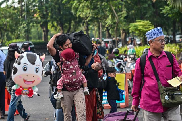 People arrive to catch free buses provided by the government to their home towns ahead of Eid al-Fitr, which marks the end of the Muslim fasting month of Ramadan in Surabaya on March 19, 2026. (Photo by JUNI KRISWANTO / AFP)