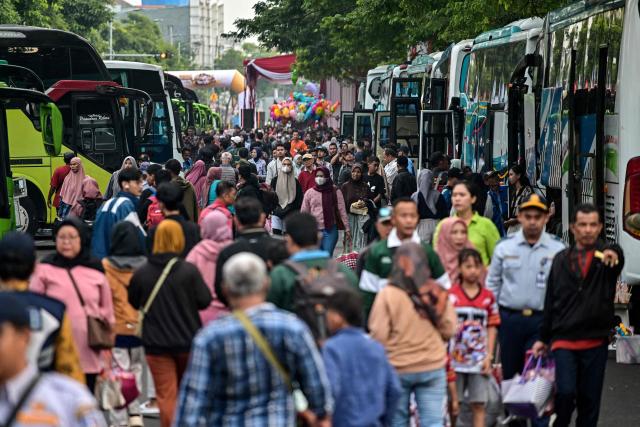 People arrive to catch free buses provided by the government to their home towns ahead of Eid al-Fitr, which marks the end of the Muslim fasting month of Ramadan in Surabaya on March 19, 2026. (Photo by JUNI KRISWANTO / AFP)