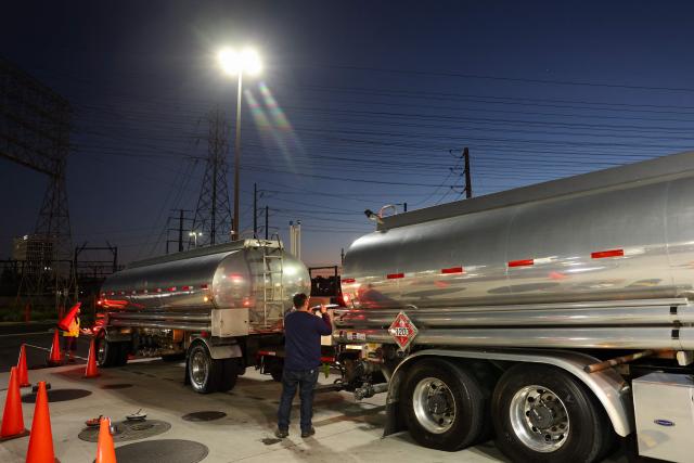 Workers prepare a tanker truck to unload a delivery of gasoline at a Costco gas station in Hawthorne, California, on March 18, 2026. Oil prices surged March 18 following a strike on a major Iranian gas facility as the Federal Reserve raised its inflation forecast while holding interest rates steady. (Photo by Patrick T. Fallon / AFP)