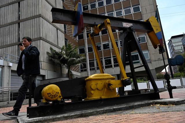 (FILES) A man walks past a pumpjack outside the Ecopetrol oil company headquarters in Bogota on March 3, 2026. Ricardo Roa, president of Colombia's state-owned oil company, announced on March 18, 2026, the discovery of an offshore gas field near Venezuela, a “significant” find following the resumption of energy cooperation between the two countries. (Photo by Pablo VERA / AFP)