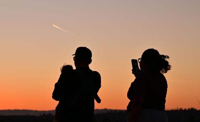 A family watches the last moments of twilight as the sun sets in Los Angeles, California, on March 18, 2026. A rare March heatwave is hitting California and the National Weather Service is warning against strenuous activity during the hottest times of the day. (Photo by Frederic J. BROWN / AFP)