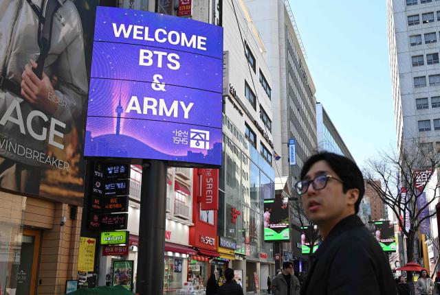 A message welcoming BTS fans is displayed on an electronic billboard at Myeongdong shopping district in Seoul on March 19, 2026, ahead of the comeback concert of K-pop boy group BTS. BTS, the world's biggest boy band, reunites on stage on March 21, in a K-pop extravaganza watched by hundreds of thousands of fans in downtown Seoul and by millions around the planet online. (Photo by Jung Yeon-je / AFP)