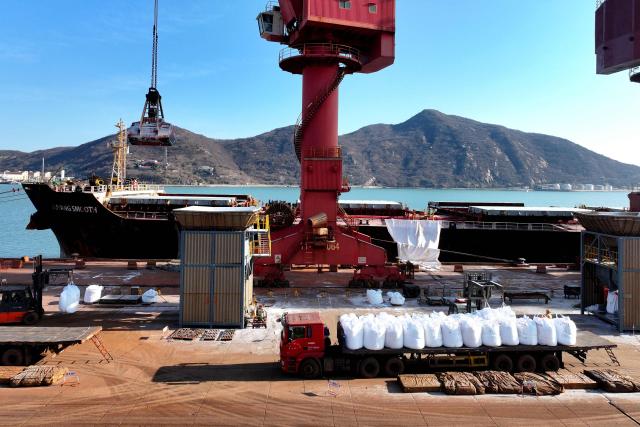 Fertilizer is unloaded from a ship at the port in Lianyungang, in China’s eastern Jiangsu province on March 19, 2026. (Photo by CN-STR / AFP) / China OUT