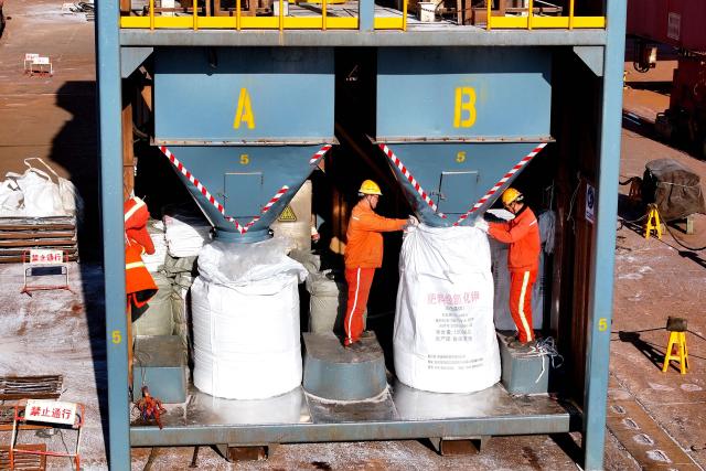 Fertilizer is bagged after being unloaded from a ship at the port in Lianyungang, in China’s eastern Jiangsu province on March 19, 2026. (Photo by CN-STR / AFP) / China OUT