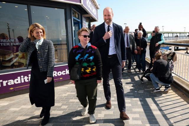 Britain's William, Prince of Wales walks with Theo from the Prince's homelessness programme Homewards National Co-Production Group and Executive Director of Homewards Hazel Detsiny, during a visit to Bournemouth pier, in Bournemouth, southern England on March 19, 2026. (Photo by Isabel Infantes / POOL / AFP)