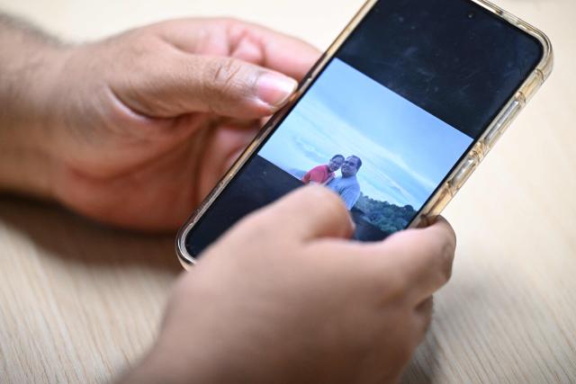 Attorney Louis Benavides, husband of human rights lawyer and head of the anti-corruption department of the NGO Cristosal, Ruth Lopez, shows a photo of himself and his wife during an AFP interview in San Salvador on March 16, 2026. In an interview with AFP on March 16, 2026, Louis Benavides, the husband of the renowned human rights activist, stated that Salvadoran lawyer Ruth Lуpez embodies “decency” and a “fearless” voice that Nayib Bukele’s government managed to silence solely through imprisonment. (Photo by AFP)