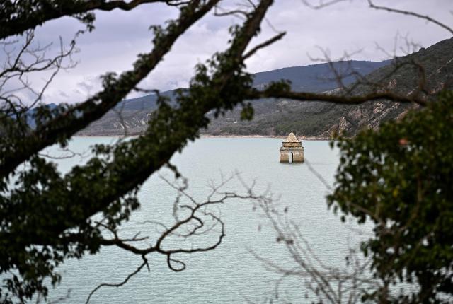 This photograph taken on March19, 2026 shows a view of the Mediano reservoir, with the Church of Asuncion of Mediano partially visible amid high water level, in Mediano, Huesca province. This long-term project shows an inventory of several sites in Spain which are suffering from drought. Photos of the same places are taken every month over a very long period. (Photo by ANDER GILLENEA / AFP)