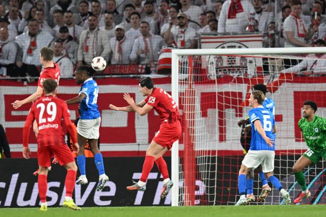 Freiburg's German defender #28 Matthias Ginter (L, top) jumps and scores the opening 1-0 goal during the UEFA Europa League, last 16 second leg, football match between SC Freiburg and KRC Genk in Freiburg, southwestern Germany, on March 19, 2026.  (Photo by THOMAS KIENZLE / AFP)