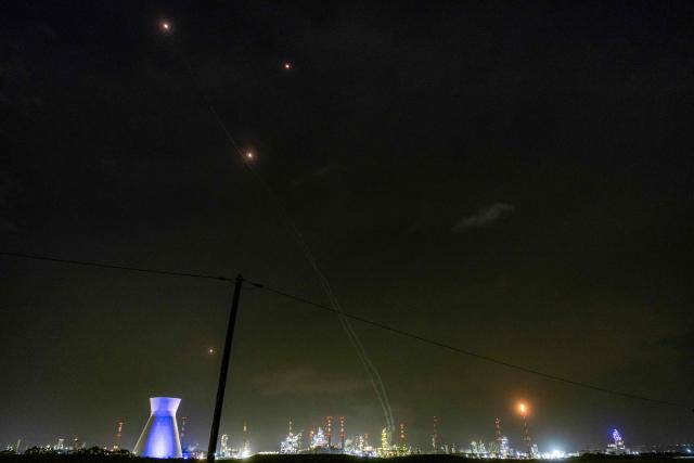 TOPSHOT - Trails and lights from missile defence interceptors are seen in the sky, as excess gas is burned at the oil refinery in Israel's northern city of Haifa late on March 19, 2026. Amid growing fears over the economic damage from the Middle East war, US President Donald Trump said there would be no repeat of Israel's attack on Iran's key South Pars gas field, but he warned of a furious US response if Tehran did not halt strikes on Qatar. Iran responded that it would have "zero restraint" if its energy infrastructure was hit again. (Photo by Odd ANDERSEN / AFP) / 