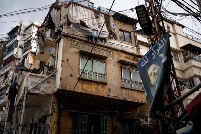 An elderly woman stands in a balcony pulling a basket filled with groceries into her apartment in Aisha Bakkar, a working-class neighbourhood of Beirut, on March 19, 2026. Lebanon was drawn into the Middle East war on March 2 when militant group Hezbollah launched rockets towards Israel to avenge the killing of Iran's supreme leader. Israel responded with intense strikes on Lebanon that have killed at least 968 people and displaced over a million, according to local authorities, and by launching ground operations in the south. (Photo by DIMITAR DILKOFF / AFP)
