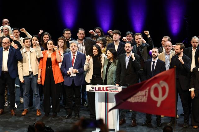 Founder of French left-wing party La France Insoumise (LFI) Jean-Luc Melenchon (C), French leftist party La France Insoumise (LFI) candidate for mayor of Lille, Lahouaria Addouche (C-R), La France Insoumise - Nouveau Front Populaire's MP Aurelien Le Coq (3rdR), La France Insoumise - Nouveau Front Populaire's MP David Guiraud (2ndR) and La France Insoumise - Nouveau Front Populaire's MP Ugo Bernalicis (R) sing with others LFI members at the end of a campaign meeting in Lille, northern France, on March 19, 2026, ahead of the second round of France's 2026 municipal elections. French voters are scheduled to head to the polls for the second round of municipal elections on March 22, 2026. (Photo by Sameer AL-DOUMY / AFP)