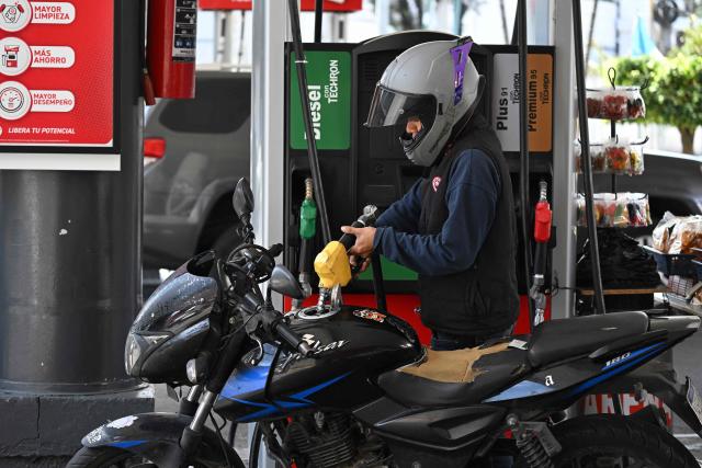 A biker holds a fuel pump at a gas station in Guatemala City on March 19, 2026. The prices of petroleum derivatives soared in Guatemala due to the war in the Middle East. (Photo by JOHAN ORDONEZ / AFP)