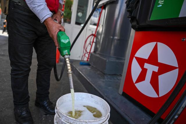 A worker fills a bucket with diesel at a gas station in Guatemala City on March 19, 2026. The prices of petroleum derivatives soared in Guatemala due to the war in the Middle East. (Photo by JOHAN ORDONEZ / AFP)