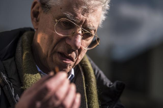 (FILES) Former leader and founder of far-right party League (Lega), Umberto Bossi, smokes a cigar in the courtyard of Palazzo delle Stelline, after a meeting with newly elected League's parliamentarians, on March 9, 2018 in Milan. Umberto Bossi, founder of the Italian Far-right Party Lega Nord died on March 19, 2026 according to Italian media. (Photo by MARCO BERTORELLO / AFP)