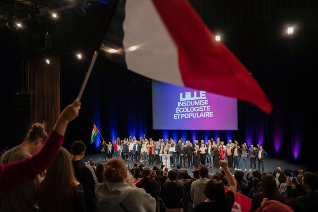 Founder of French left-wing party La France Insoumise (LFI) Jean-Luc Melenchon and French leftist party La France Insoumise (LFI) candidate for mayor of Lille, Lahouaria Addouche sing with others LFI members at the end of a campaign meeting, in Lille, northern France, on March 19, 2026, ahead of the second round of France's 2026 municipal elections. French voters are scheduled to head to the polls for the second round of municipal elections on March 22, 2026. (Photo by Elise HOUBEN / AFP)