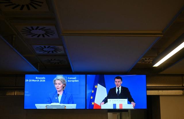 Screens showing European Commission President Ursula von der Leyen and France's President Emmanuel Macron are seen in a press room during the EU Summit at the EU headquarters in Brussels, on March 19, 2026. European Union leaders meet in the context of the US-Israeli war against Iran that is consuming the Middle East, and its consequences on energy prices and security. (Photo by NICOLAS TUCAT / AFP)