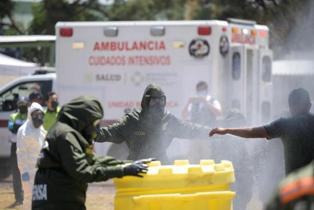 Soldiers wearing gasoline-resistant protective gear respond to an accident involving a gas tanker as part of ‘Exercise Ollamani’ at the Santa Lucia Military Base in the municipality of Zumpango, State of Mexico, Mexico, on March 19, 2026. "Exercise Ollamani" is organized by various institutions—including the Mexican Army, the National Guard, and the Attorney General's Office—and serves as an anti-terrorism drill designed to safeguard the 2026 World Cup. (Photo by Alfredo ESTRELLA / AFP)