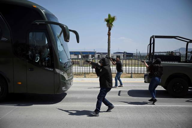 Soldiers dressed in civilian clothing participate as assailants during a simulated bus-robbery exercise as part of ‘Exercise Ollamani’ at the Santa Lucia Military Base in the municipality of Zumpango, State of Mexico, Mexico, on March 19, 2026. "Exercise Ollamani" is organized by various institutions—including the Mexican Army, the National Guard, and the Attorney General's Office—and serves as an anti-terrorism drill designed to safeguard the 2026 World Cup. (Photo by Alfredo ESTRELLA / AFP)