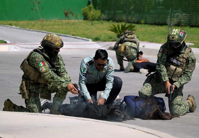 Mexican soldiers and a National Guard agent take part in a simulated kidnapping of a government official as part of ‘Exercise Ollamani’ at the Santa Lucia Military Base in the municipality of Zumpango, State of Mexico, Mexico, on March 19, 2026. "Exercise Ollamani" is organized by various institutions—including the Mexican Army, the National Guard, and the Attorney General's Office—and serves as an anti-terrorism drill designed to safeguard the 2026 World Cup. (Photo by Alfredo ESTRELLA / AFP)