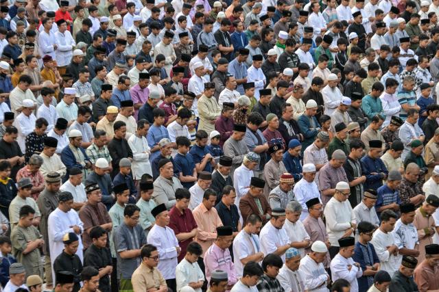 Muslim devotees offer Eid al-Fitr morning prayer along a road in Surabaya on March 20, 2026, marking the end of holy month of Ramadan. (Photo by JUNI KRISWANTO / AFP)