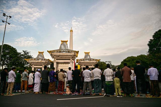 Muslim devotees offer Eid al-Fitr morning prayer along a road in Surabaya on March 20, 2026, marking the end of holy month of Ramadan. (Photo by JUNI KRISWANTO / AFP)