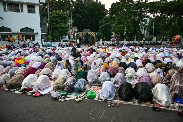 Muslim devotees offer Eid al-Fitr morning prayer along a road in Surabaya on March 20, 2026, marking the end of holy month of Ramadan. (Photo by JUNI KRISWANTO / AFP)