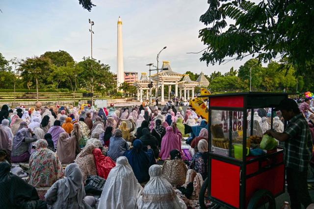 Muslim devotees offer Eid al-Fitr morning prayer along a road in Surabaya on March 20, 2026, marking the end of holy month of Ramadan. (Photo by JUNI KRISWANTO / AFP)