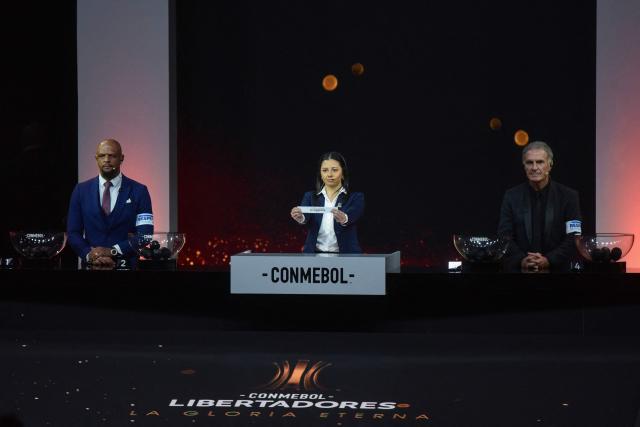 Conmebol Competition Manager Luciana Antunez (C) shows the slip of Brazil's Fluminense alongside former football players Felipe Melo (L) of Brazil and Oscar Ruggeri of Argentina during the Copa Libertadores group-stage draw in Luque, Asuncion, on March 19, 2026. (Photo by DANIEL DUARTE / AFP)
