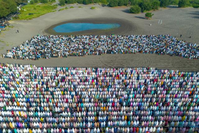 This aerial picture shows Muslim devotees from the Muhammadiyah organization performing the Eid al-Fitr prayer, marking the end of the holy month of Ramadan, at Parangkusumo Beach in Bantul, Yogyakarta on March 20, 2026. (Photo by DEVI RAHMAN / AFP)