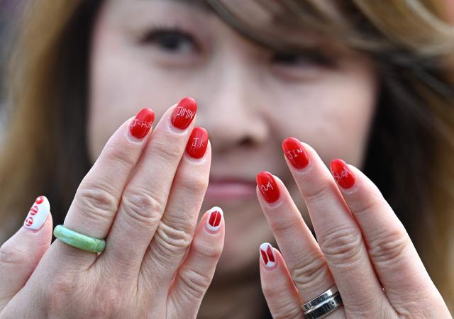 A woman shows nail art featuring the names of BTS members as she visits a fan zone promoting the new album of K-pop boy band BTS at a riverside park in Seoul on March 20, 2026. K-pop megastars BTS release the new album "ARIRANG" on March 20, billed as reflecting the maturing boy band's Korean roots and identity, as buzz builds ahead of their open-air comeback concert in the heart of Seoul. (Photo by Jung Yeon-je / AFP)