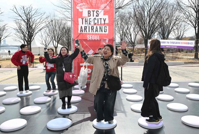 BTS fans enjoy themselves at a fan zone promoting the new album of K-pop boy band BTS at a riverside park in Seoul on March 20, 2026. K-pop megastars BTS release the new album "ARIRANG" on March 20, billed as reflecting the maturing boy band's Korean roots and identity, as buzz builds ahead of their open-air comeback concert in the heart of Seoul. (Photo by Jung Yeon-je / AFP)