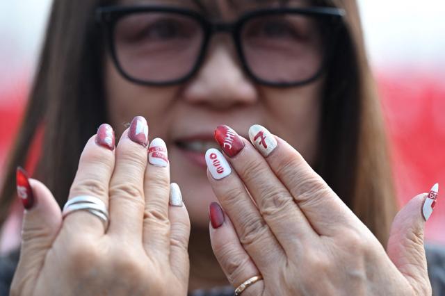 A woman shows nail art featuring BTS logo as she visits a fan zone promoting the new album of K-pop boy band BTS at a riverside park in Seoul on March 20, 2026. K-pop megastars BTS release the new album "ARIRANG" on March 20, billed as reflecting the maturing boy band's Korean roots and identity, as buzz builds ahead of their open-air comeback concert in the heart of Seoul. (Photo by Jung Yeon-je / AFP)