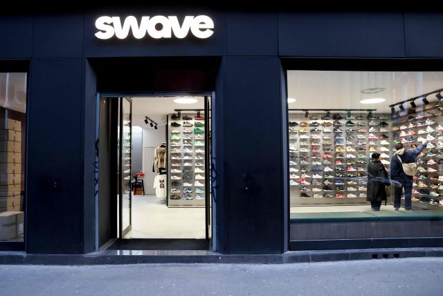 Clients look at sneakers displayed at the Swave store of funder Hugo Carvalho, in Paris March 12, 2026. Teleshopping isn’t dead; it’s just moved to mobile: combining live video with instant purchasing, ‘live shopping’ is revolutionising online retail, prompting tech giants, brands and small shops alike to get on board. ‘Starting price: one euro... 20 seconds to bid. 3, 2, 1, go!’ Sitting in front of his multiple screens, Hugo Carvalho, founder of the Parisian shop Swave, which specialises in collectable trainers, is shouting himself hoarse live on the Whatnot app. (Photo by ALAIN JOCARD / AFP)