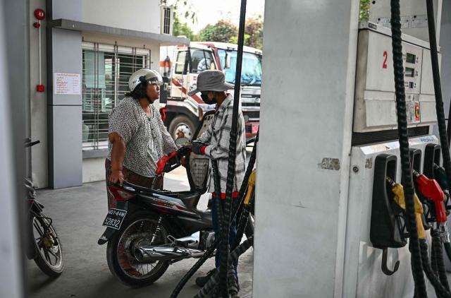 An employee refuels a vehicle at a petrol station amid rising prices in Mandalay on March 20, 2026. (Photo by Sai Aung MAIN / AFP)