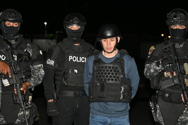 Ecuador’s police officers escort Ecuadorian drug trafficker Angel Aguilar, alias ‘Lobo Menor’, as he arrives at the Aeropolicial facilities at the airport in Guayaquil on March 19, 2026. Colombia’s migration authority reported on Marche 18, 2026 the arrest of Ecuadorian drug trafficker Angel Aguilar, who is linked to the assassination in Quito of presidential candidate Fernando Villavicencio one week before the 2023 elections. (Photo by Marcos PIN / AFP)