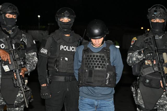 Ecuador’s police officers escort Ecuadorian drug trafficker Angel Aguilar, alias ‘Lobo Menor’, as he arrives at the Aeropolicial facilities at the airport in Guayaquil on March 19, 2026. Colombia’s migration authority reported on Marche 18, 2026 the arrest of Ecuadorian drug trafficker Angel Aguilar, who is linked to the assassination in Quito of presidential candidate Fernando Villavicencio one week before the 2023 elections. (Photo by Marcos PIN / AFP)